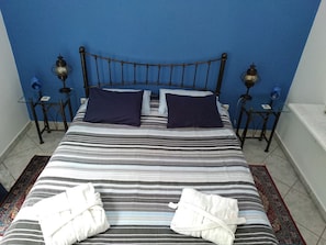 A bed with striped bedding, two pillows, and two white towels. - Seafarer's Suite (Delphi)