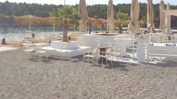 Un restaurante frente a la playa con terraza, sombrillas y vistas al mar.
