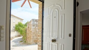Una puerta blanca con manija de latón que da a un balcón con vistas a una calle y edificios.