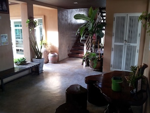 Stylish interior with a high ceiling, staircase, and lush greenery.