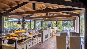 A spacious outdoor dining area with a long counter, multiple chairs, and a view of the surrounding greenery. - Vallegrande Nature Resorts (Cefalù)