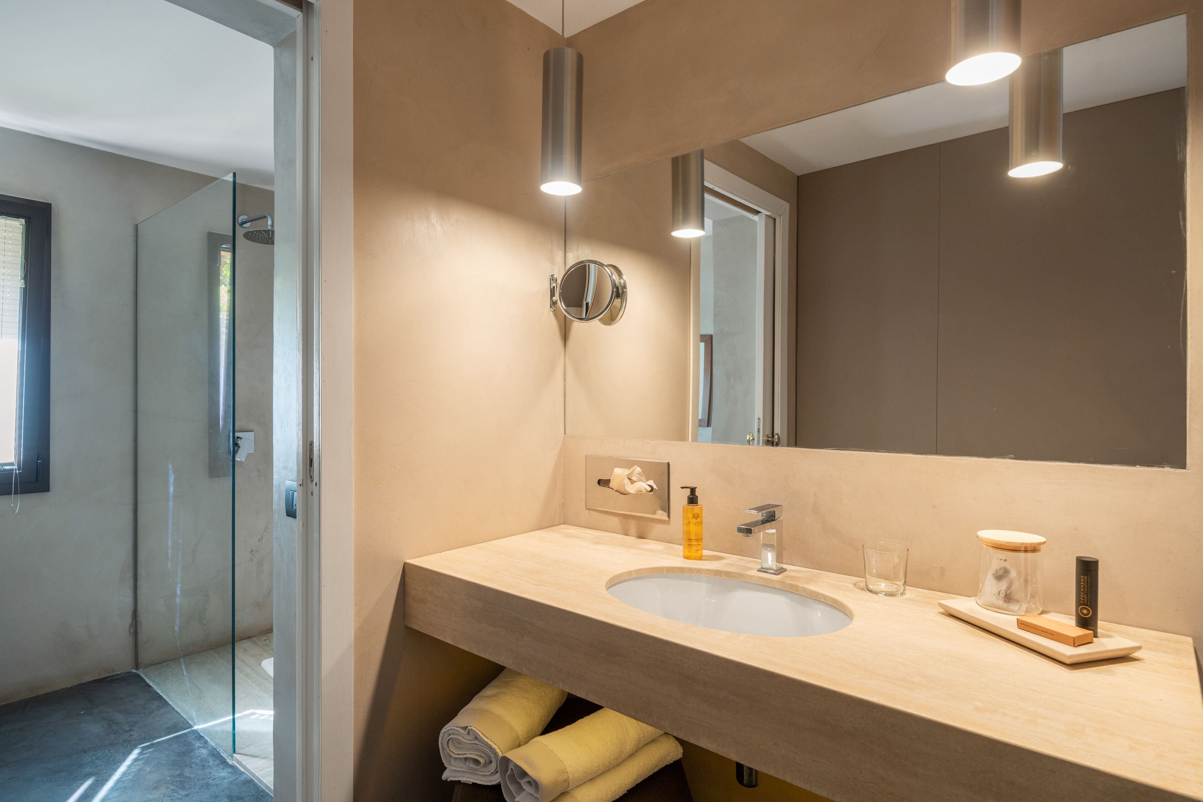 Un baño moderno con un lavabo color beige, un espejo y una cabina de ducha de vidrio.
