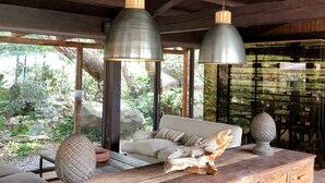 A modern interior with a wooden ceiling, a sofa, and a dining area with a stone ball centerpiece. - Vallegrande Nature Resorts (Cefalù)