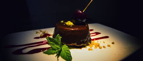 En dessert på en hvid tallerken foran en mørk baggrund.