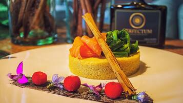 Un plat composé de saumon, de légumes verts et d’une base jaune, peut-être du couscous, présenté sur une assiette agrémentée d’éléments décoratifs.