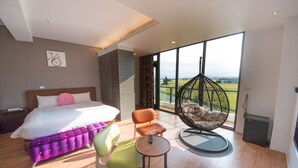 A modern hotel room with a large bed, a hanging chair, a small table, and a view of the outdoors. - Tsaiyu B&B (Zhuangwei)