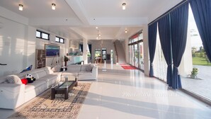 A spacious living room with a large window, a staircase leading to an upper level, and a modern design. - Tsaiyu B&B (Zhuangwei)