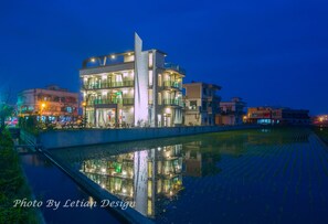 Un edificio moderno de varios pisos y balcones, reflejado en el agua.