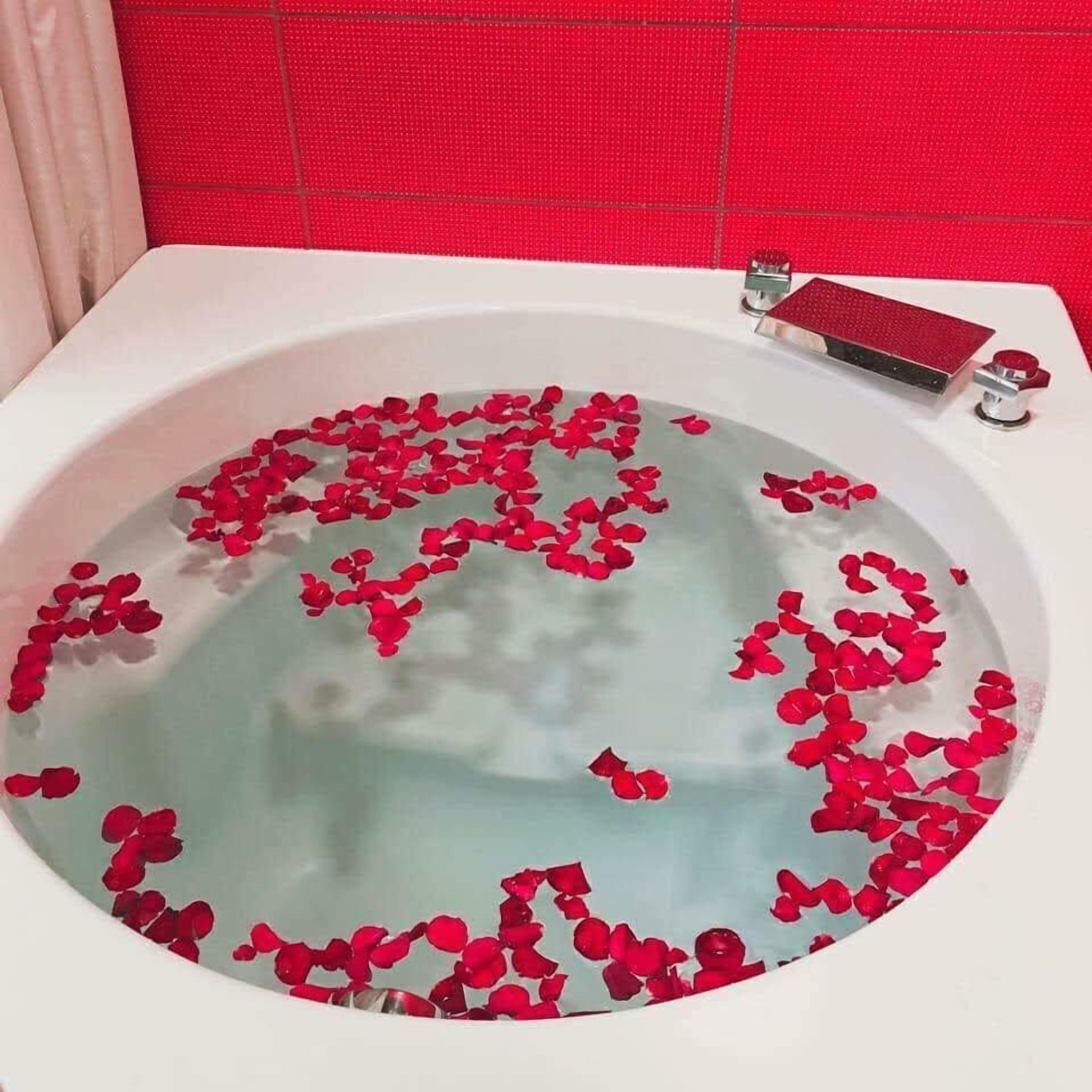 A bathtub filled with water and rose petals.
