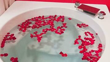 A bathtub filled with water and rose petals.