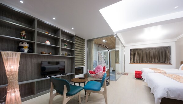 Una habitación de hotel moderna con televisión, zona de estar, sillón colgante y cama.