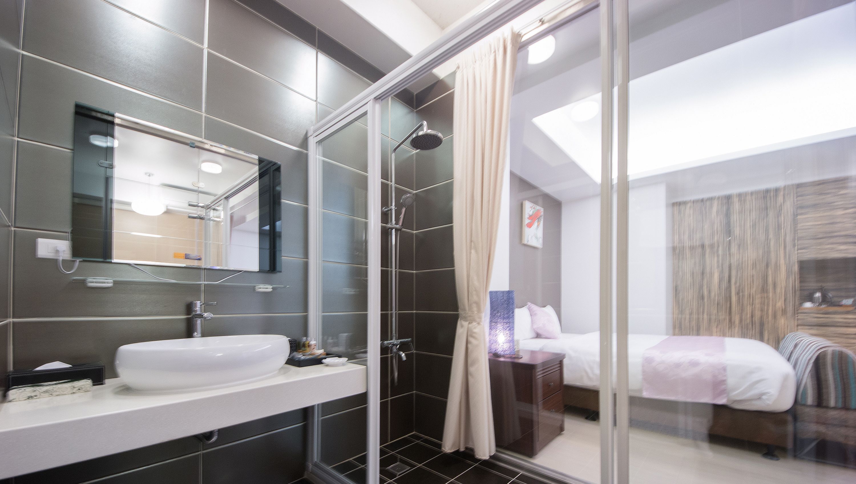 Un baño moderno con cabina de ducha de vidrio, un espejo grande y un lavabo blanco.