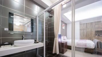 Un baño moderno con cabina de ducha de vidrio, un espejo grande y un lavabo blanco.