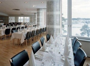 A restaurant with multiple tables set for dining, large windows with a view, and a modern interior design.