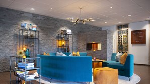 A modern lounge area with blue sofas, a wooden coffee table, and a metal bookshelf. - Skogshem & Wijk (Lidingo)