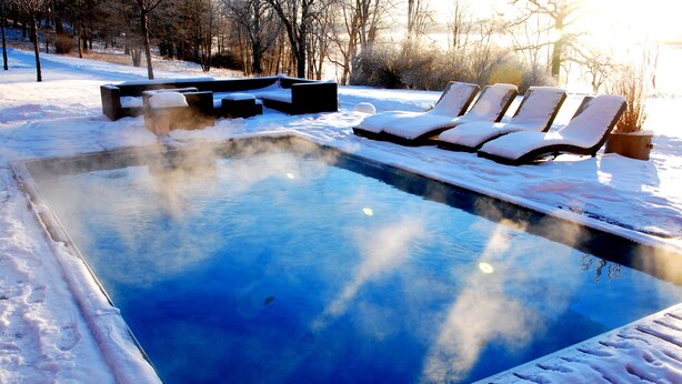 A snow-covered outdoor swimming pool with lounge chairs and a hot tub. - Skogshem & Wijk (Lidingo)