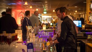 A bar area with a bartender, bar counter, and various bottles and glasses. - Skogshem & Wijk (Lidingo)