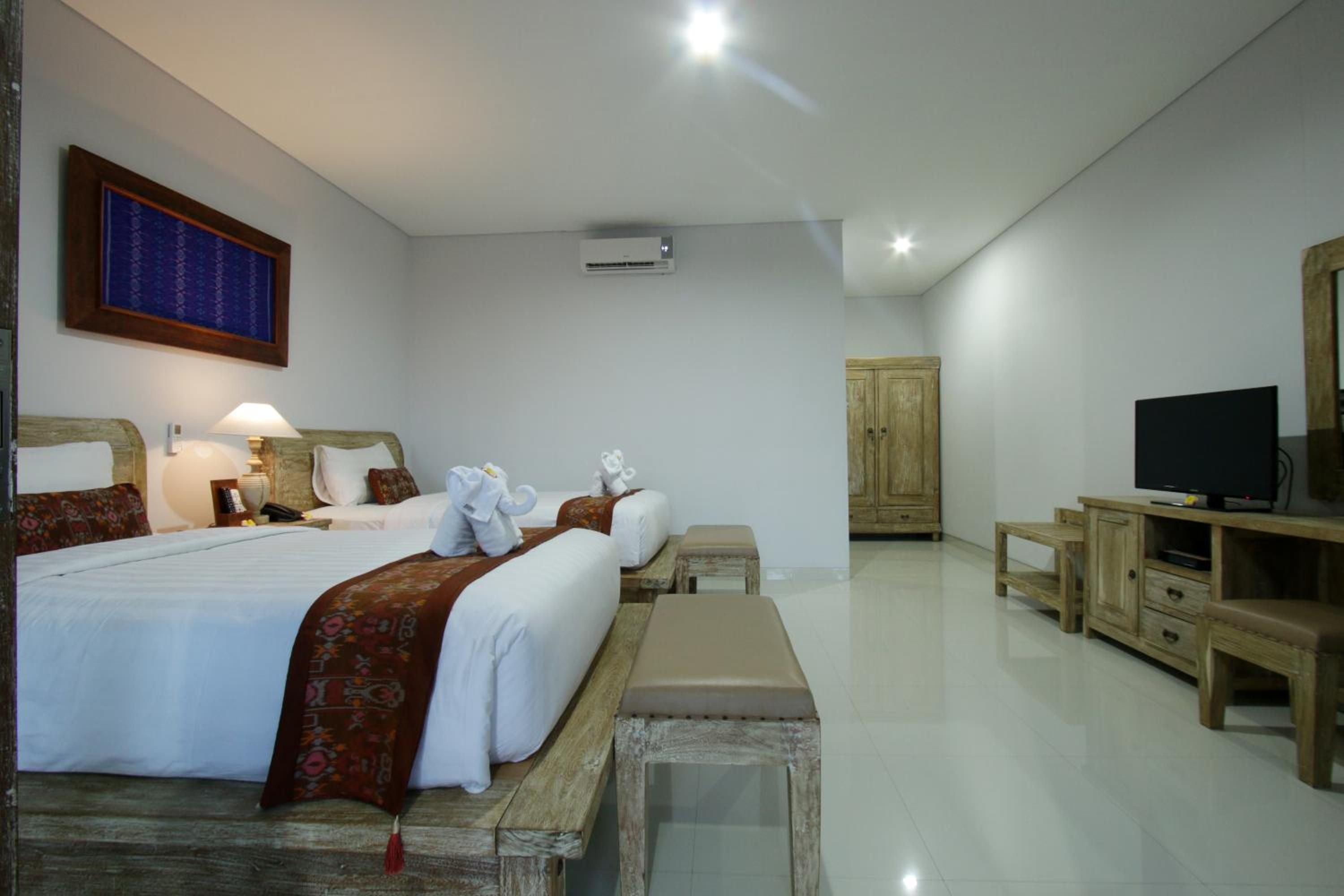 A hotel room with a large bed, bedside tables, a TV, and a wardrobe.