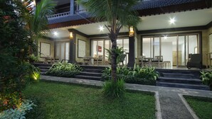 A traditional-style building with a covered entrance, steps leading up to a seating area, and a well-maintained garden. - Batu Empug Ubud Cottages (Ubud)