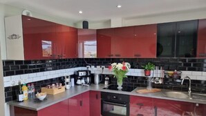 Una cocina moderna con armarios rojos, salpicadero negro, electrodomésticos de acero inoxidable y encimera de madera.