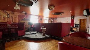 Un restaurante con escenario, asientos rojos y piso de madera.