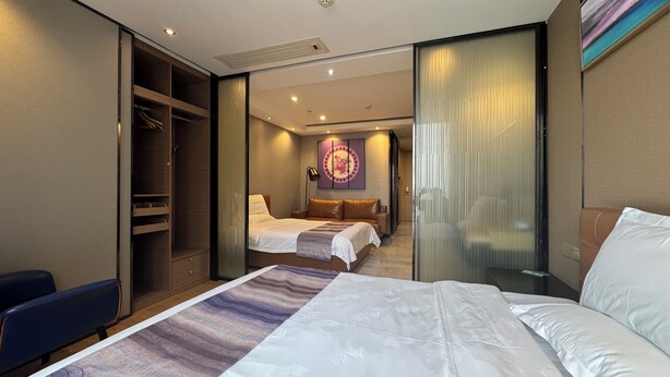 A hotel room with a large bed, a smaller bed, a walk-in closet, and a view of the room through a glass partition. - Green Lemon Tree International Apartment - Beijing Road Jiedeng Metropolis Branch (Guangzhou)