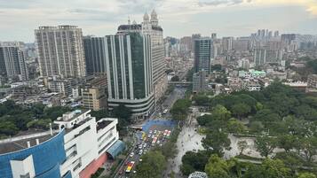 A cityscape with high-rise buildings, a curved modern building with a blue roof, and a busy street with vehicles and pedestrians.