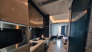 A modern kitchen with stainless steel appliances, a dining area with a table and chairs, and a bedroom with a bed and curtains. - Green Lemon Tree International Apartment - Beijing Road Jiedeng Metropolis Branch (Guangzhou)