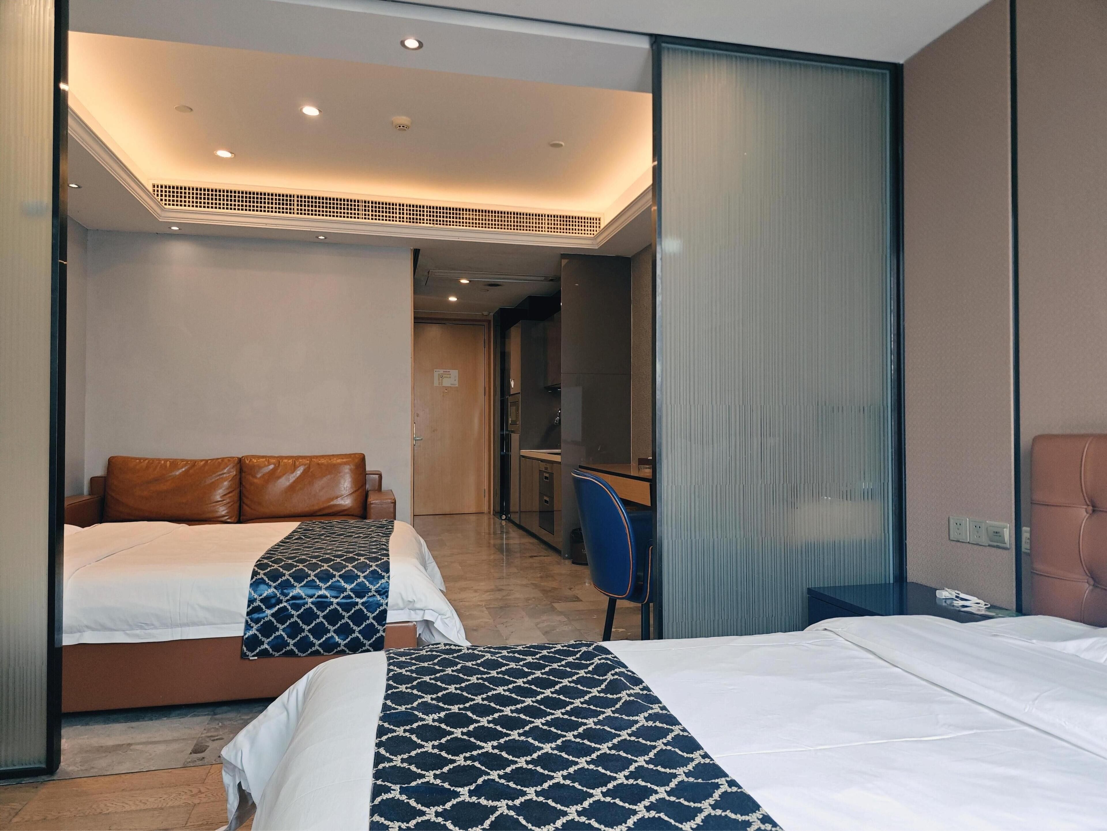 A hotel room with two beds, a desk, and a mirror.