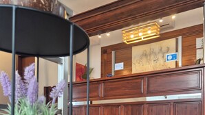 A reception area with a wooden counter, a potted plant, and a marble floor. - Varmy (Ierapetra)