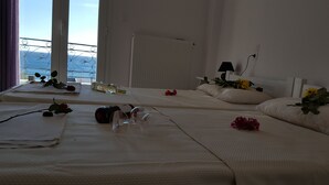 A hotel room with two beds, a view of the sea through a balcony, and a radiator on the wall. - Varmy (Ierapetra)