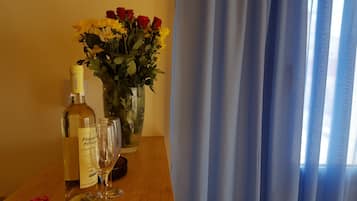 Una mesa con una botella de vino, dos copas y un florero con flores.