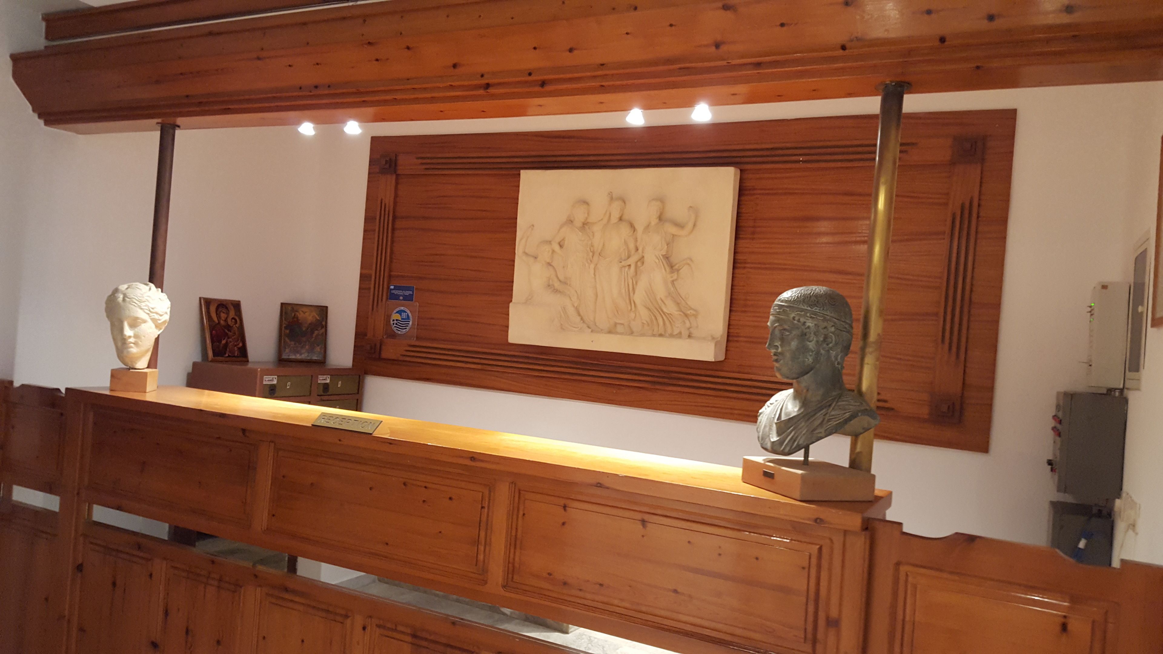Ein Empfangsschalter mit Holzvertäfelung, zwei Büsten und ein gerahmtes Kunstwerk an der Wand.