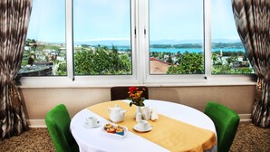A room with a table set for tea, a view of a lake, and a cityscape. - Cukurova Erten Otel (Adana)