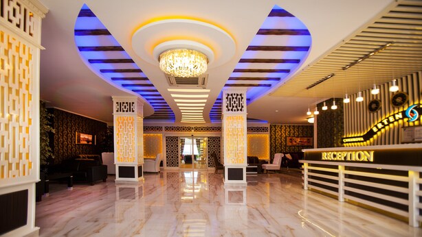 A hotel reception area with a marble floor, a chandelier, and a reception desk. - Cukurova Erten Otel (Adana)
