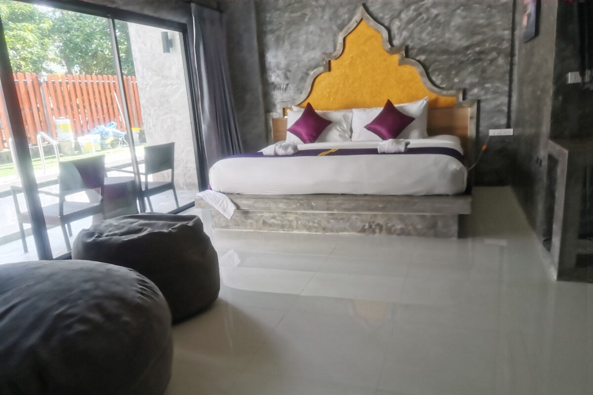A bedroom with a bed, a bench, and a view of the outside.