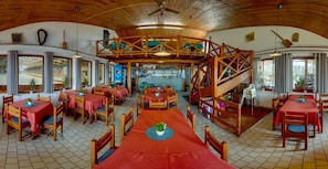 A restaurant with multiple tables and chairs, a bar area, and a wooden staircase. - HOTEL PANSKA LICHA (BRNO)
