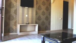 Una habitación con una televisión de pantalla plana en la pared, una mesita consola de madera y una mesa de centro negra.