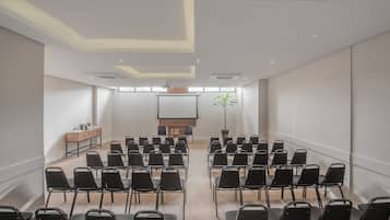 A conference room with rows of chairs, a podium, and a projector screen.