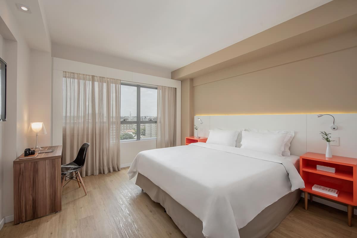 Een moderne hotelkamer met een groot bed, een bureau en een stoel.