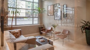 Een modern interieur met een bank, stoelen, een salontafel en grote ramen met uitzicht op de straat.