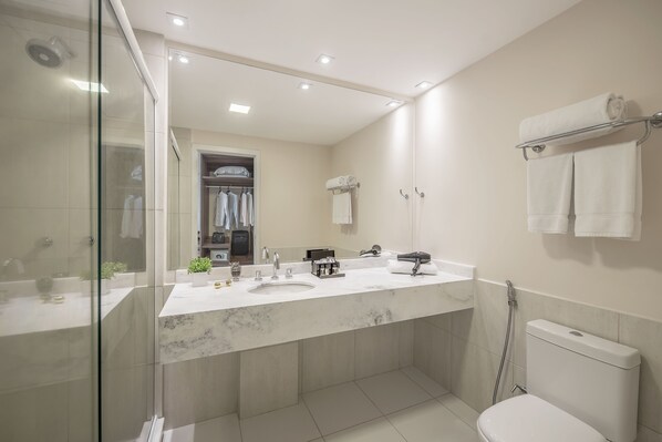 A modern bathroom with a glass shower enclosure, a double sink vanity, and a toilet. - Intercity Curitiba Centro Cívico (Curitiba)