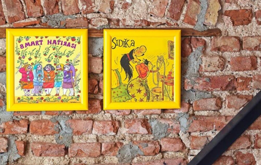 Deux œuvres d’art encadrées sont accrochées à un mur de briques.