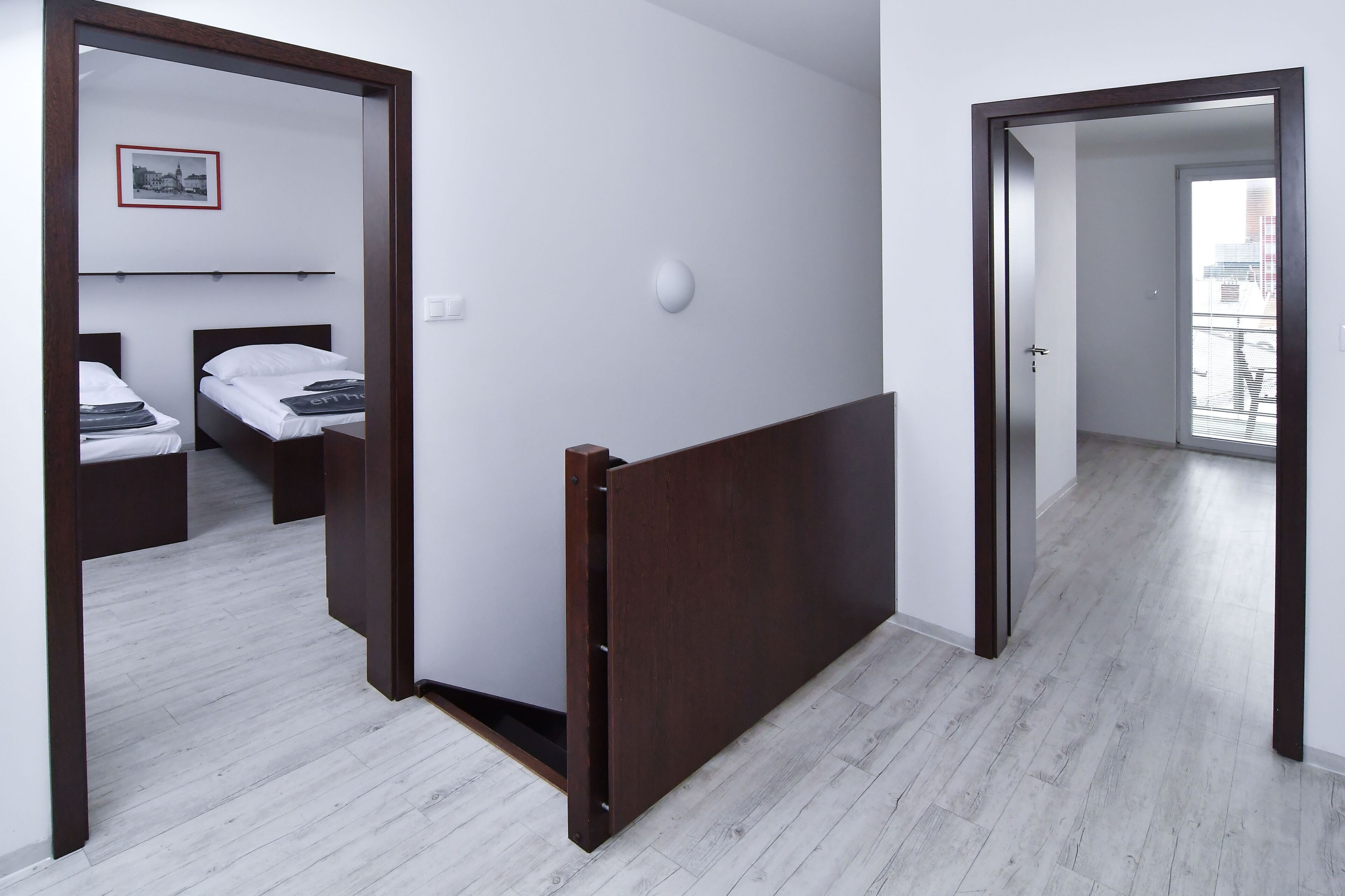A hotel room with a bed, bedside tables, a mirror, and a window.
