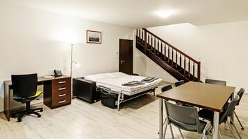 Habitación pequeña con cama, escritorio, silla y una escalera.