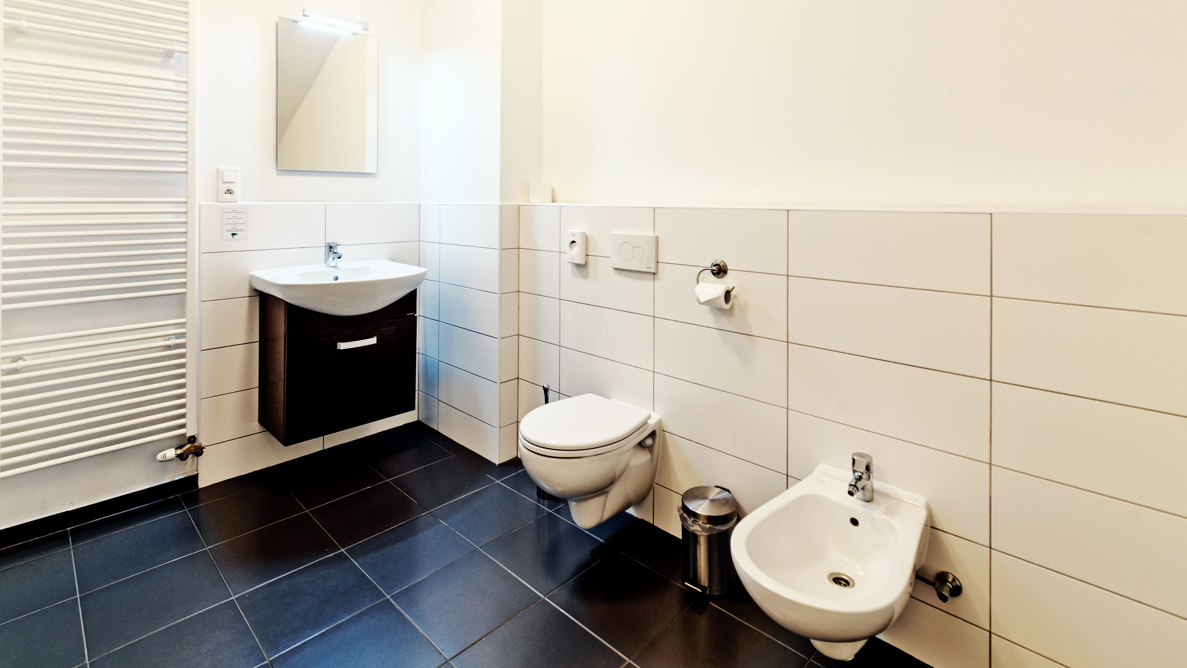 A modern bathroom with a toilet, bidet, and sink.