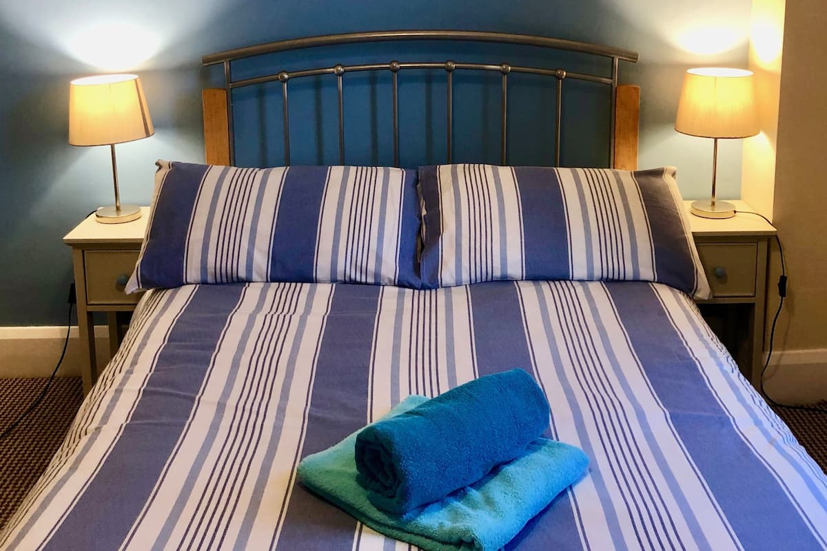 A bed with striped bedding, two bedside lamps, and a framed picture on the wall.