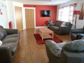 A living room with leather sofas, a wooden coffee table, and a red rug.