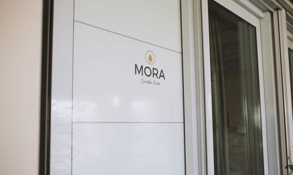 Een gevel van een gebouw met een logo en de tekst 'MORA Garden Suite'.
