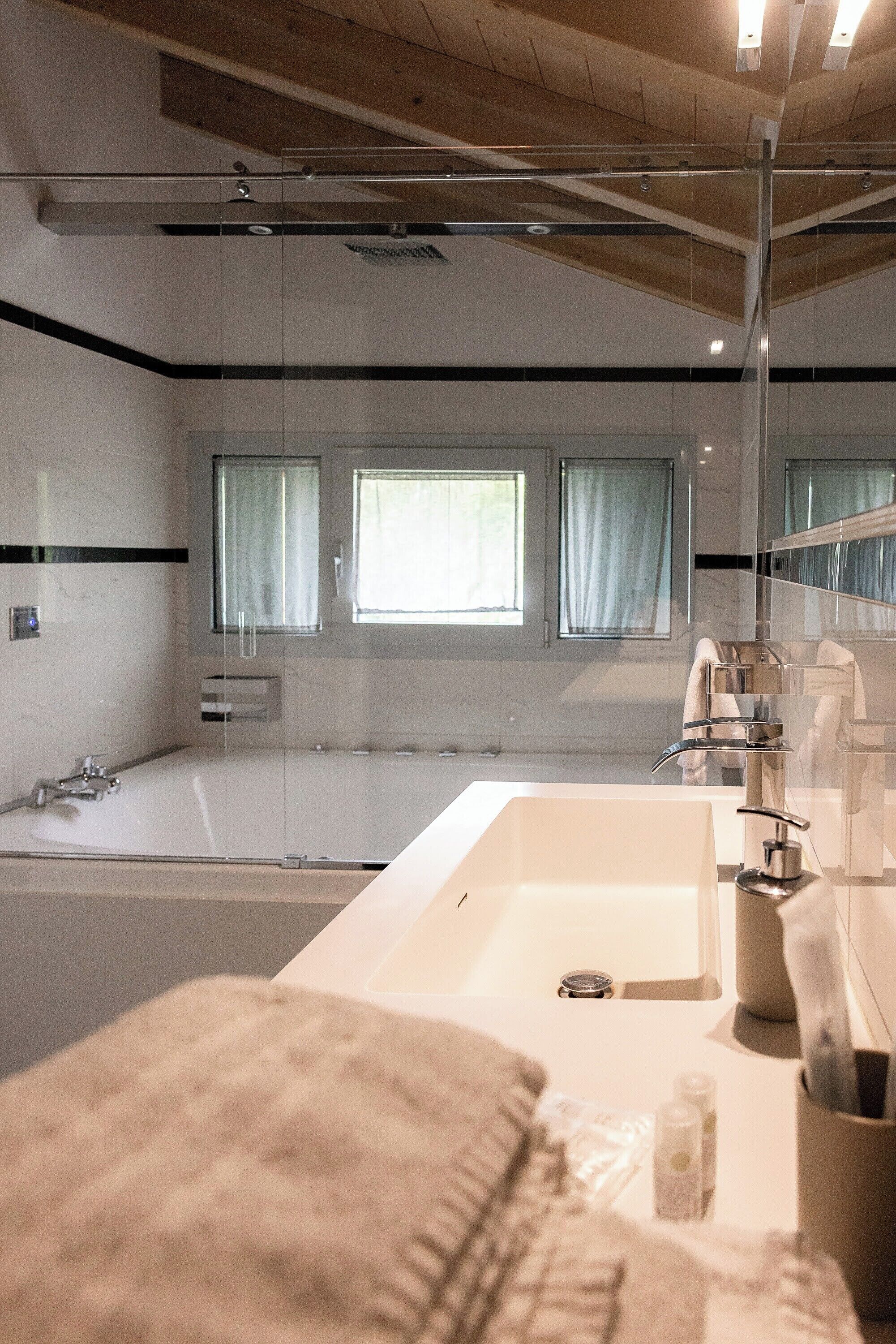A modern bathroom with a large bathtub, a glass shower enclosure, and a vanity with a mirror.